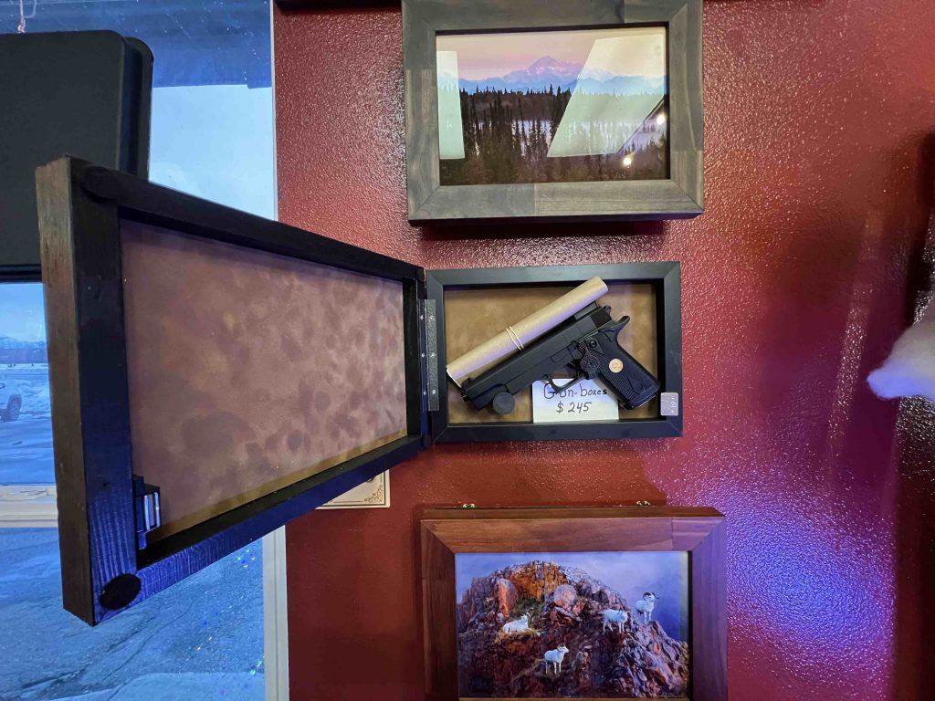 Gun Box picture frame hanging on the gallery wall opened showing a prop gun hidden inside..